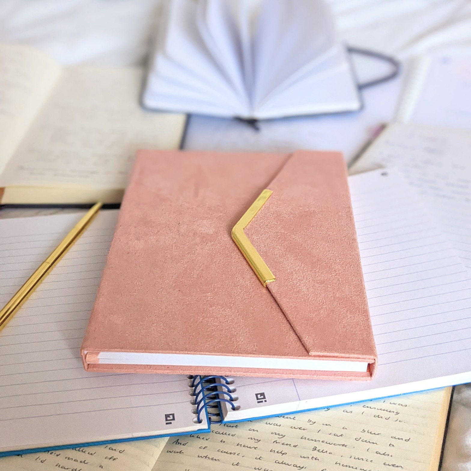 A picture of a pile of notebooks and a pen
